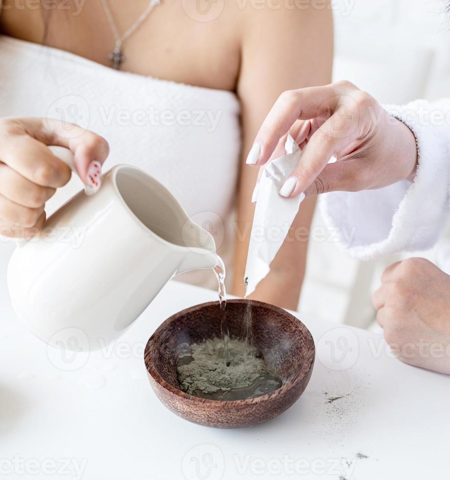 mãos femininas fazendo máscara facial realizando procedimentos de spa foto