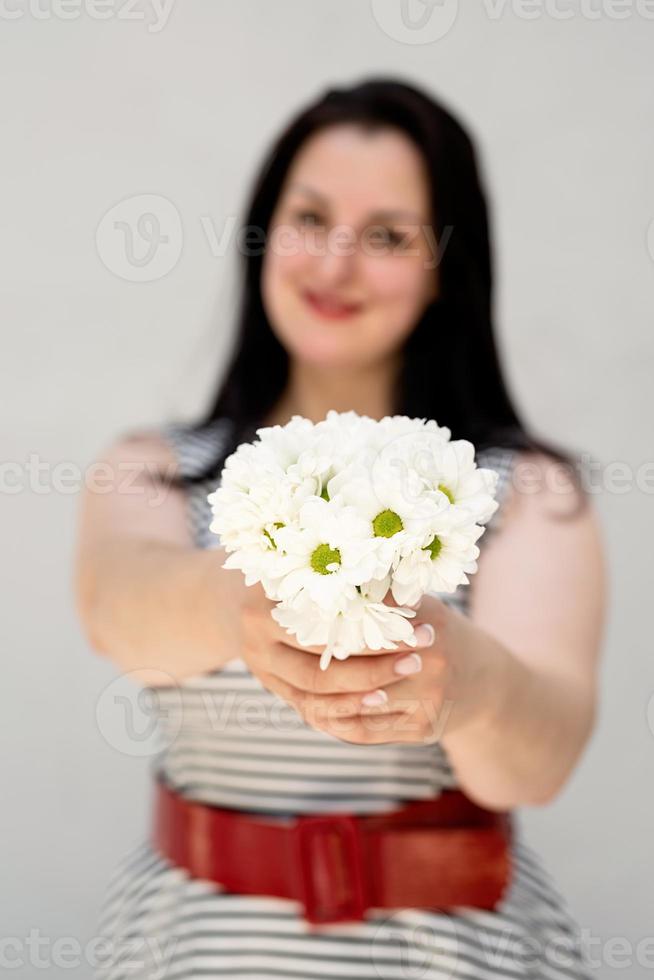 jovem segurando um buquê de flores em um fundo cinza sólido foto
