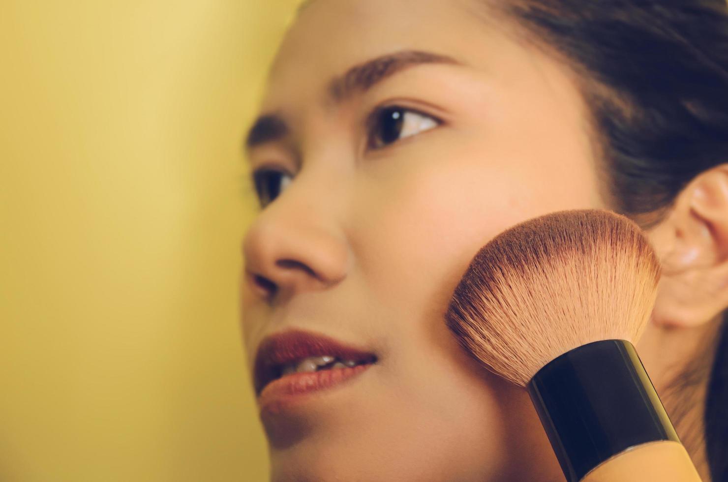 rosto de beleza de mulher asiática, aplicando pincéis na pele por cosméticos. foto