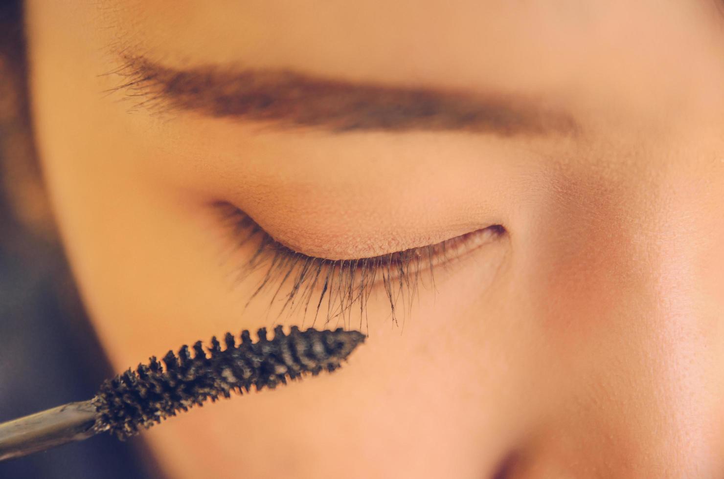 rosto de beleza da mulher, aplicando rímel no olho por cosméticos. foto