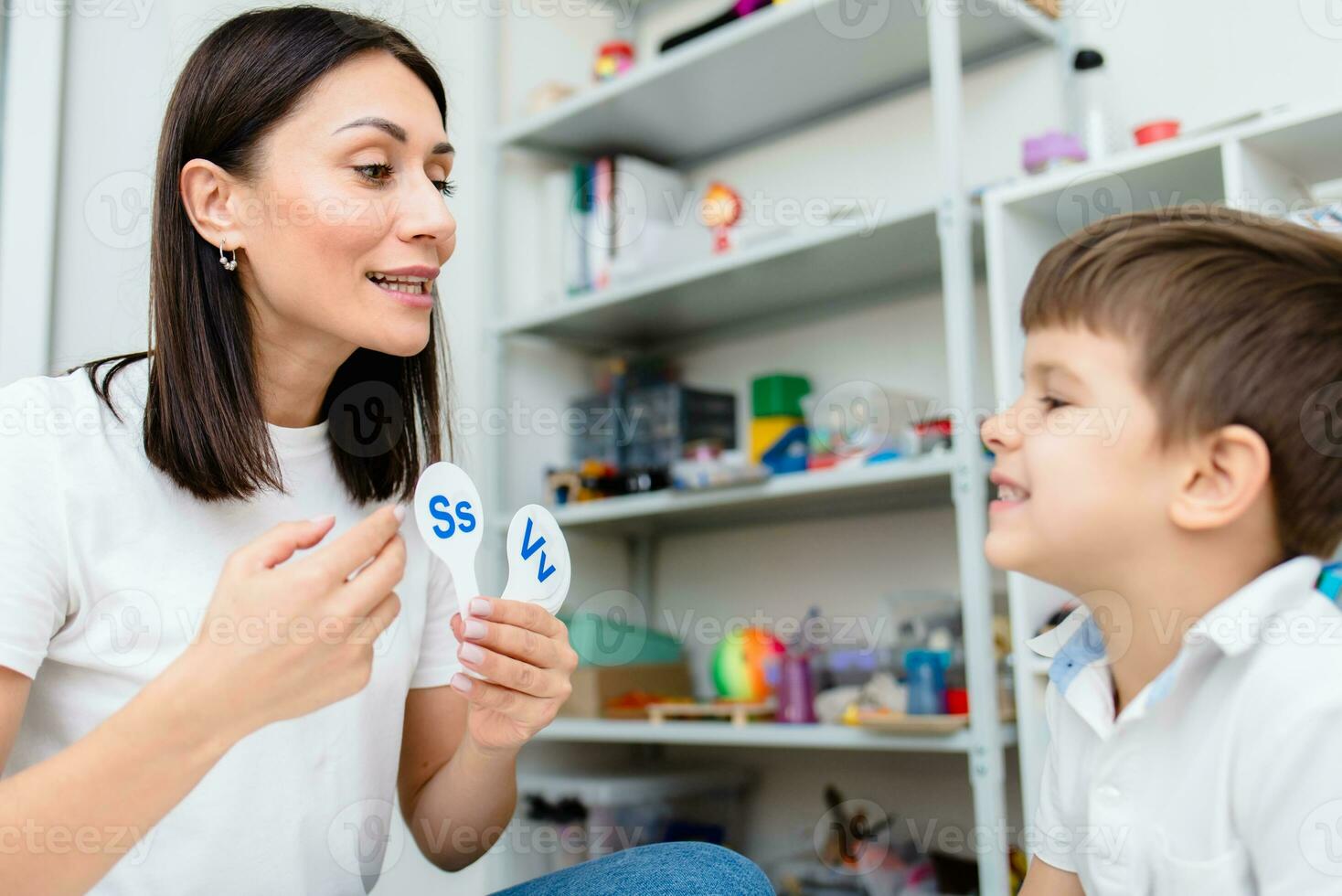 uma fofa Garoto com uma discurso terapeuta é ensinado para pronunciar a cartas, palavras e sons. foto