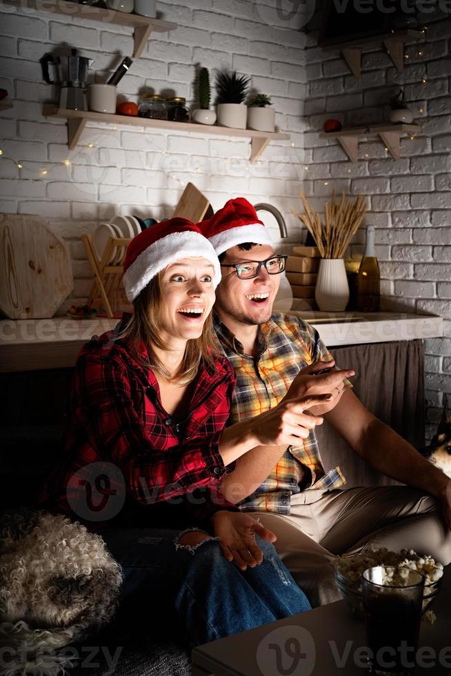 casal assistindo filmes em casa no natal apontando para a tela foto