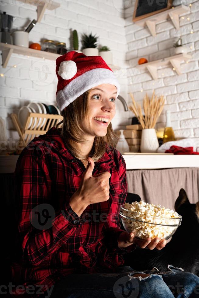 mulher assistindo filmes em casa na noite de natal comendo pipoca foto