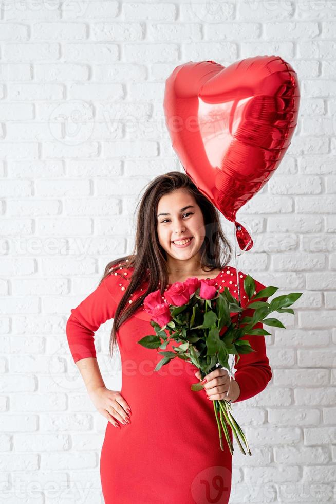 mulher segurando flores e um balão de coração vermelho foto