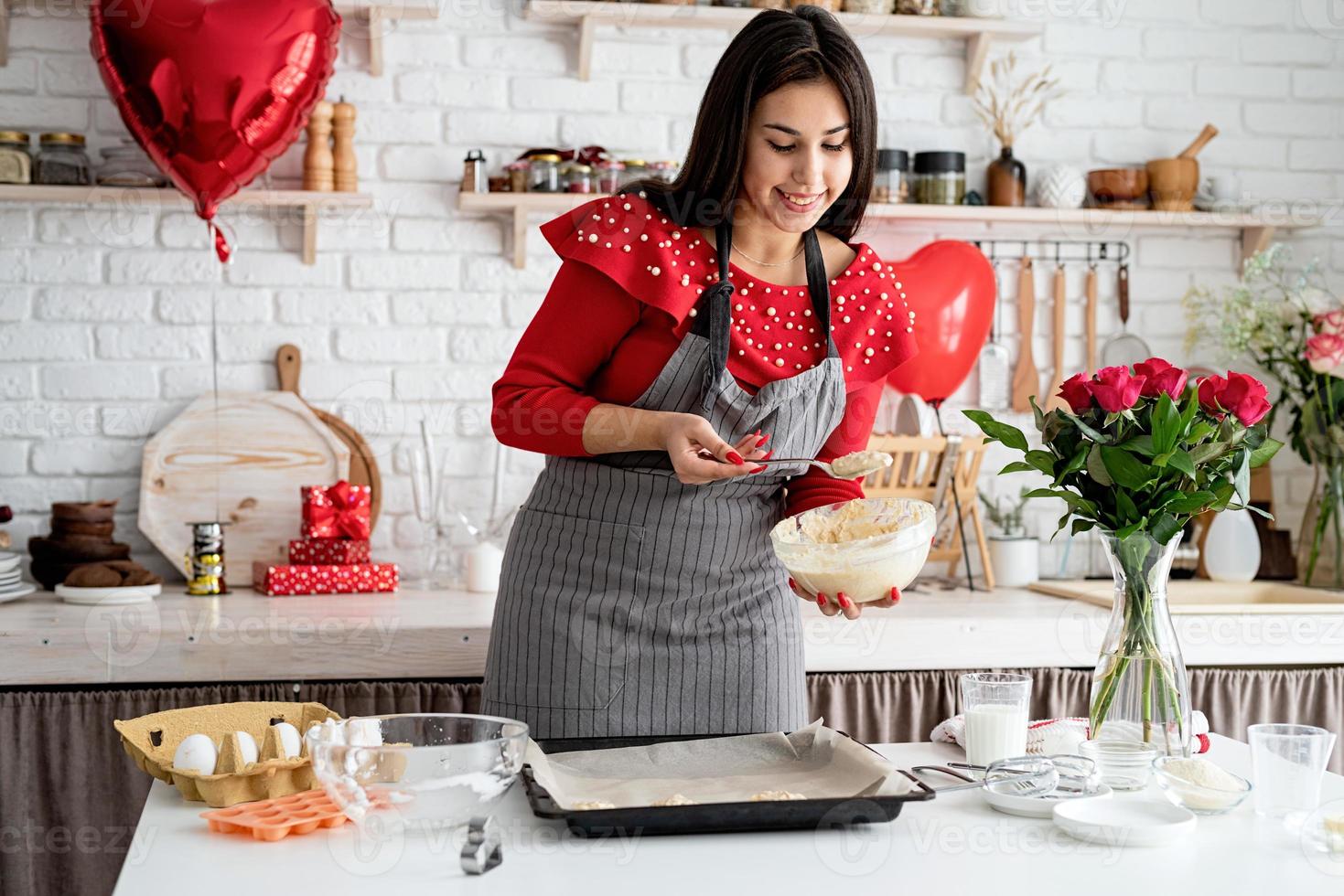 mulher fazendo biscoitos para o dia dos namorados na cozinha foto