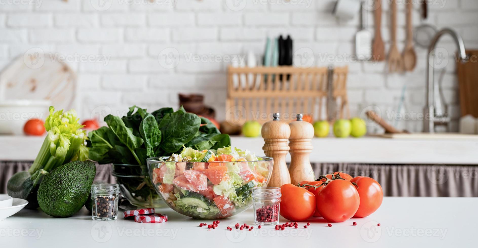 vista frontal da mesa da cozinha com uma tigela de salada grega e ingredientes foto