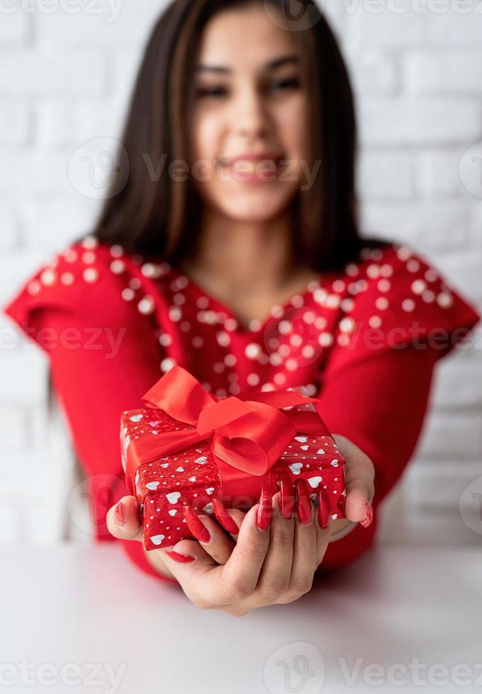 mulher de vestido vermelho segurando um presente para o dia dos namorados foto