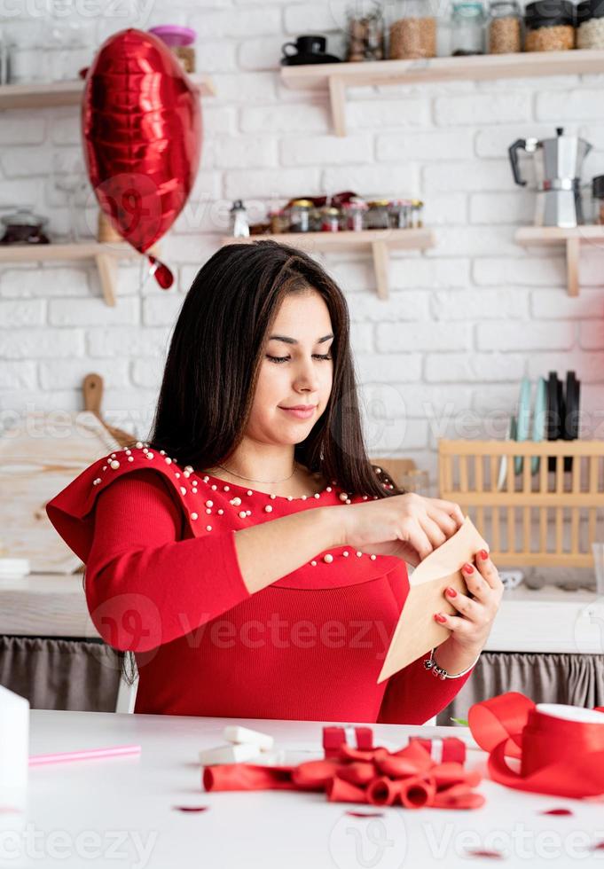 mulher escrevendo carta de amor sentada na cozinha decorada foto