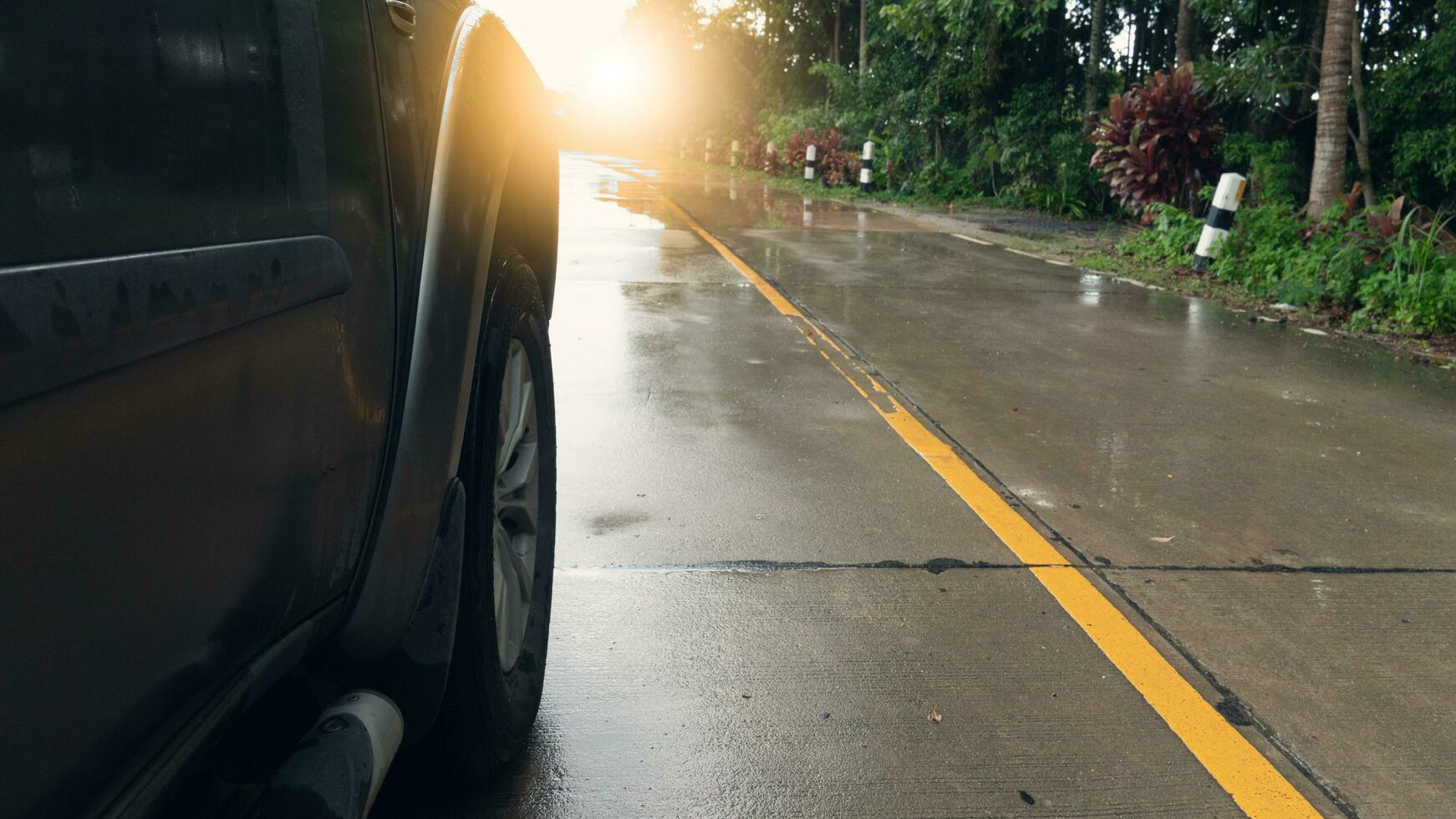 frente Visão do uma carro com uma foco em a rodas do uma carro corrida em uma molhado concreto estrada. molhado de chuva rural floresta ambiente. foto