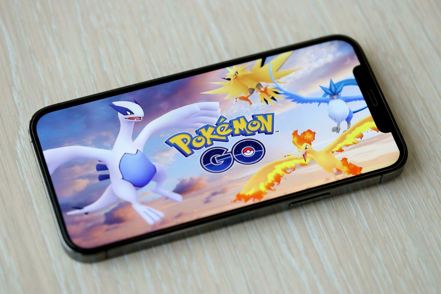 Pokémon ir Móvel ios jogos em Iphone 15 Smartphone tela em de madeira mesa durante Móvel jogabilidade foto
