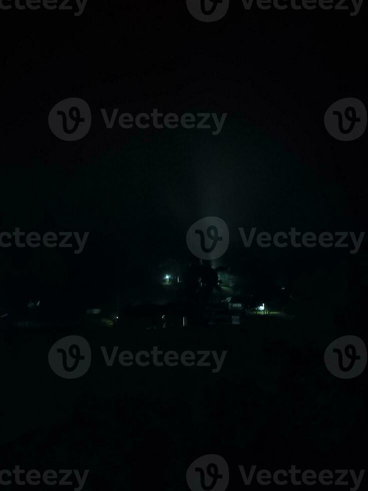 abeto árvores em Prado entre encostas com coníferas floresta dentro névoa debaixo a azul céu às noite. assustador campo cenário dentro cheio lua luz foto