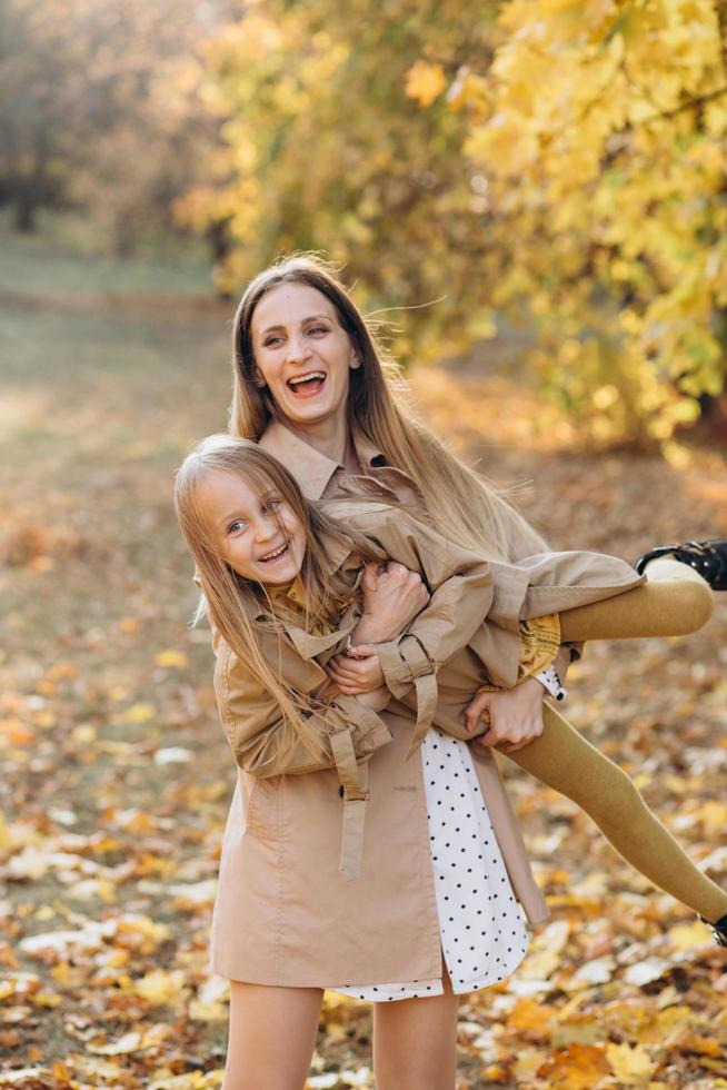 mãe e filha se divertem e caminham no parque outono. foto