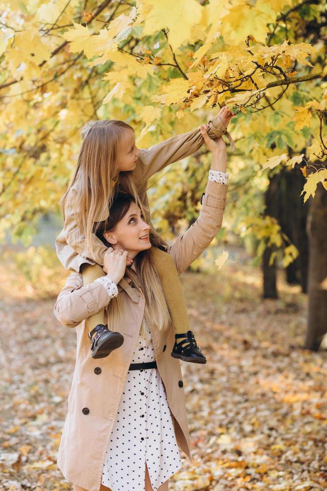 mãe e filha se divertem e caminham no parque outono. foto