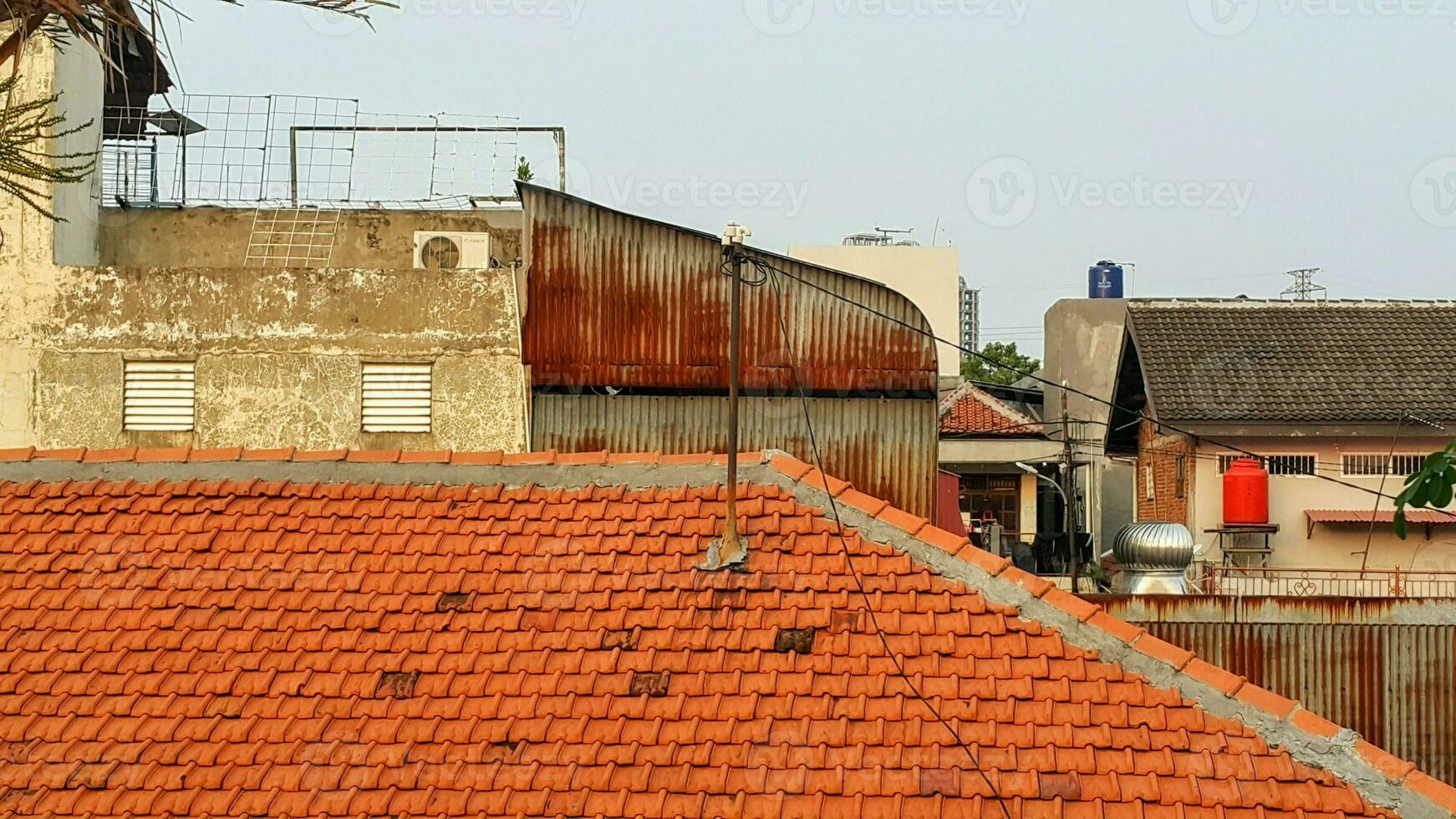 Visão do a cobertura do a velho casa e a azul céu. a Castanho telha cobertura dentro suburbano área dentro Jacarta foto