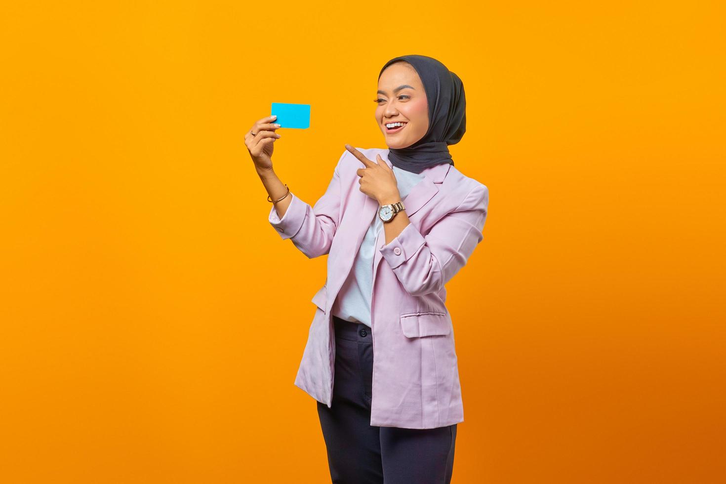 mulher asiática sorridente mostra cartão de crédito a gesticular com o dedo foto