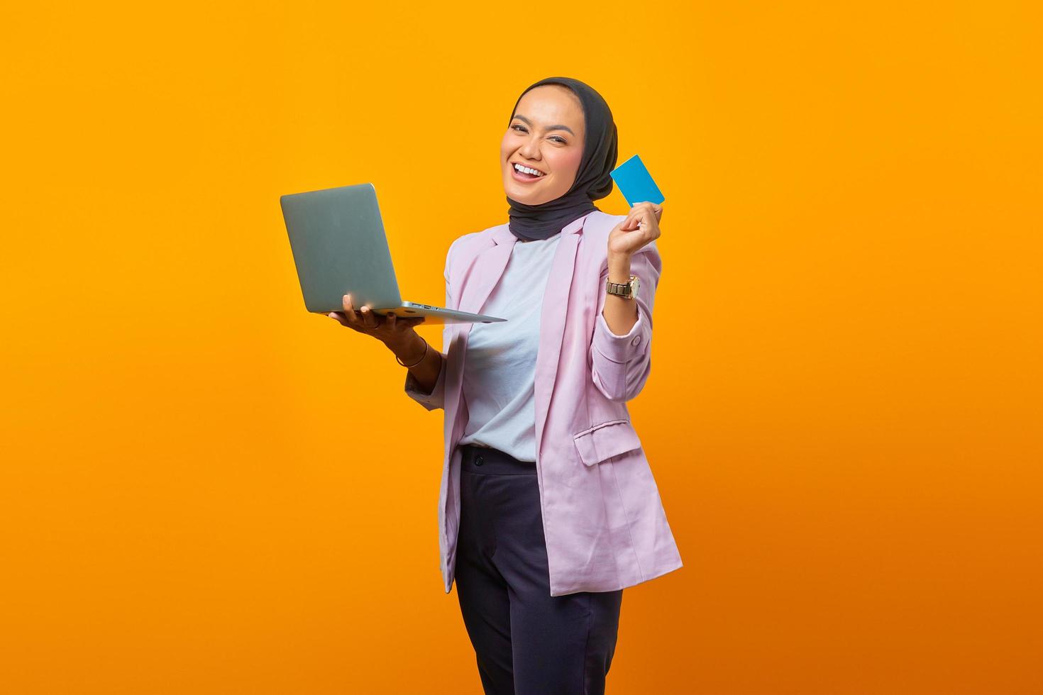 mulher asiática segurando um laptop e mostrando um cartão em branco foto