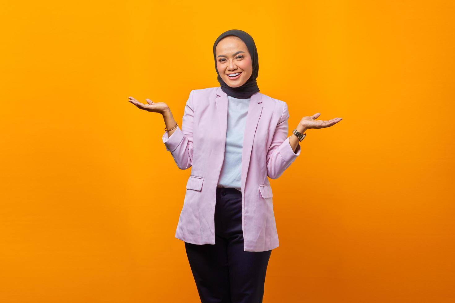 mulher asiática alegre mostrando produto sobre fundo amarelo foto