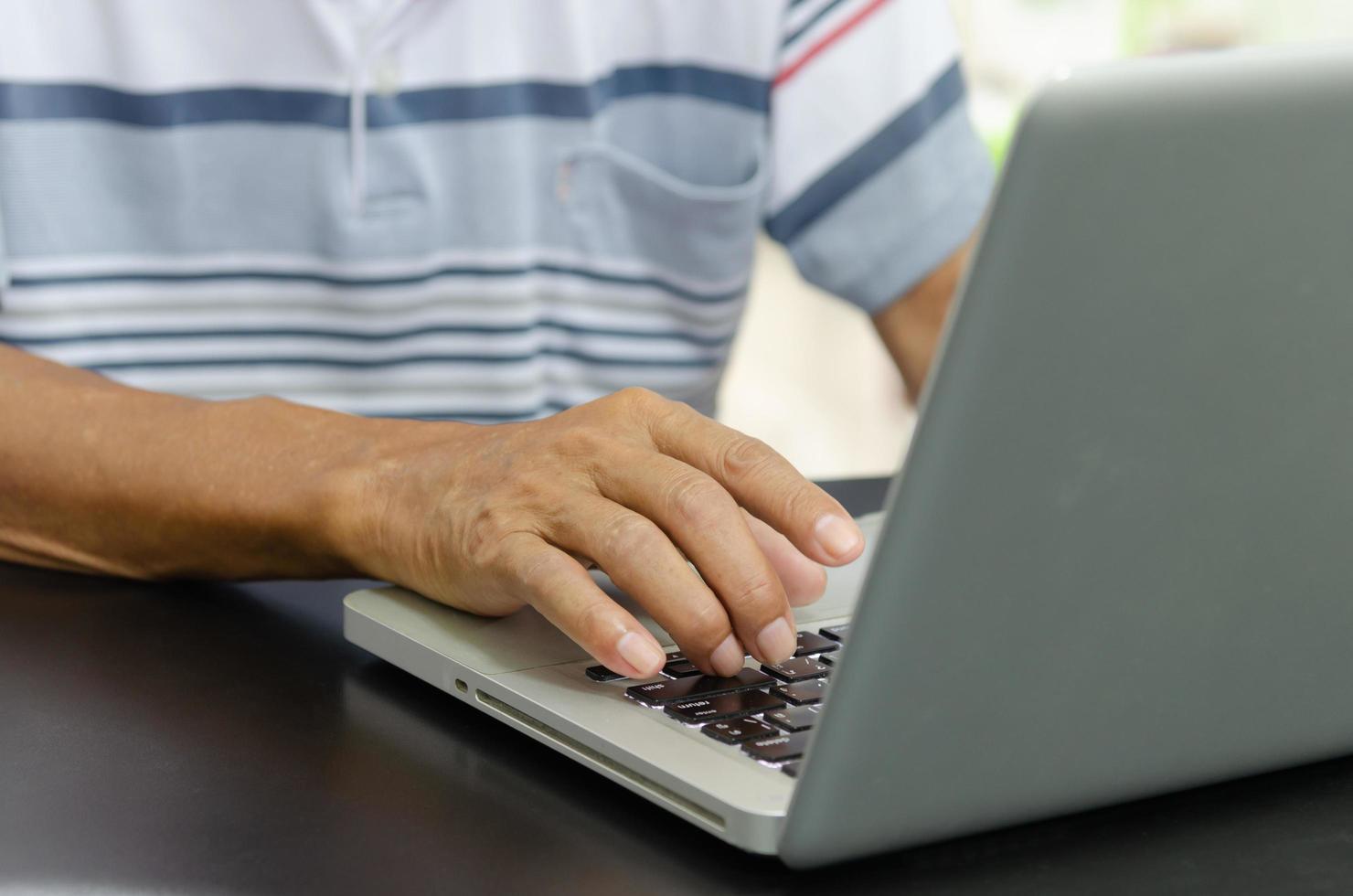 mão de homem usando computador laptop na mesa em casa foto