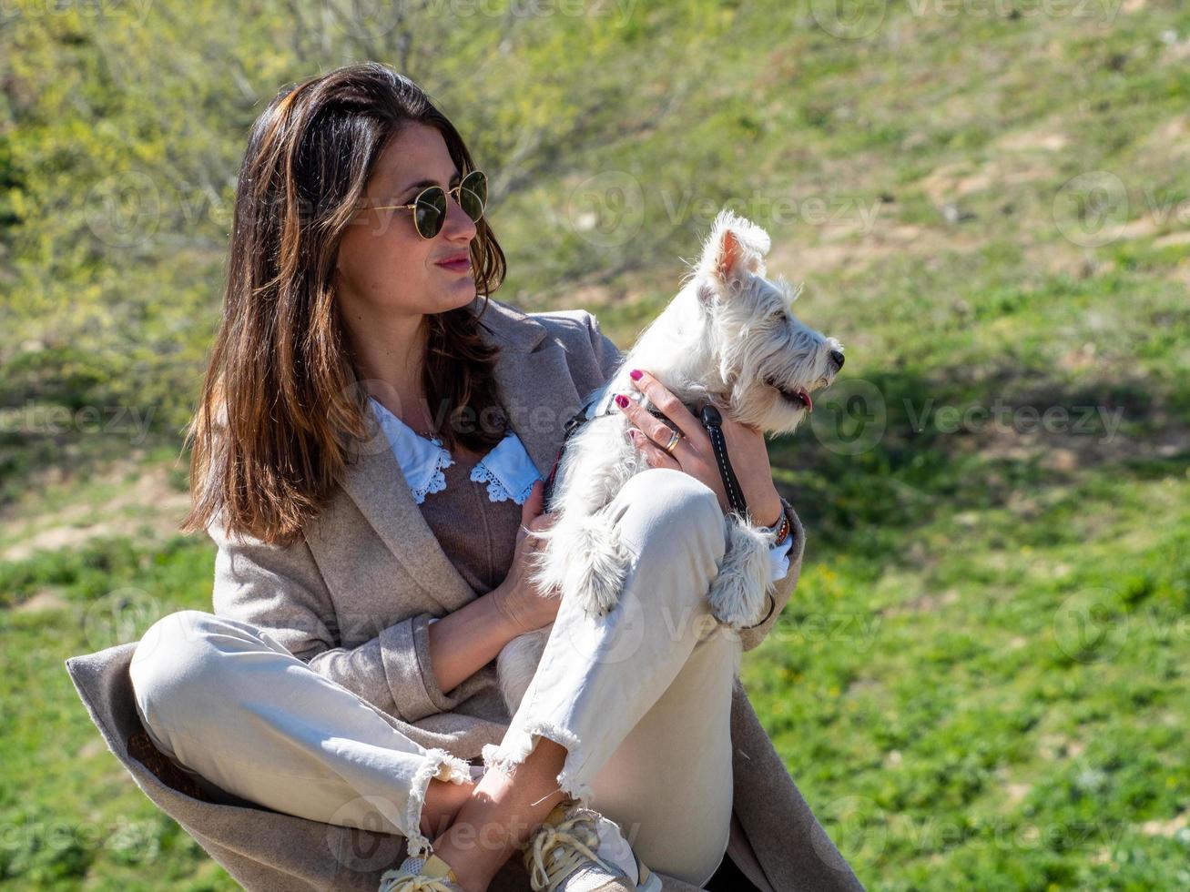 jovem posando para uma foto com seu cachorrinho schnauzer branco.