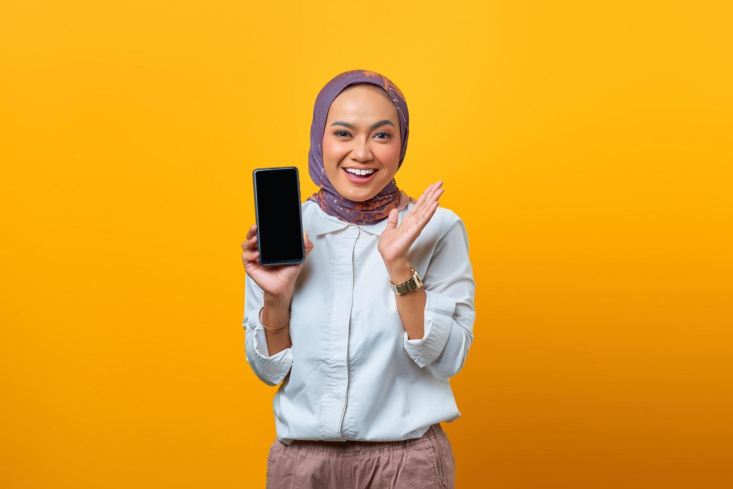 Mulher asiática sorridente mostrando a tela do smartphone em branco foto