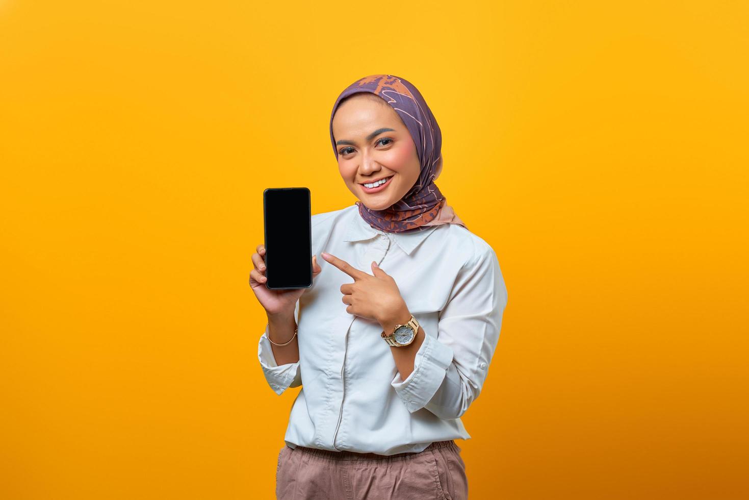 Mulher asiática sorridente mostrando a tela do smartphone em branco foto
