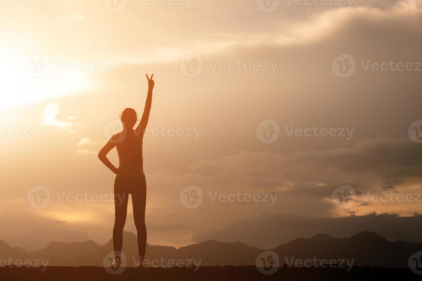 silhueta de mulher forte em pé e lutando no topo de uma montanha foto