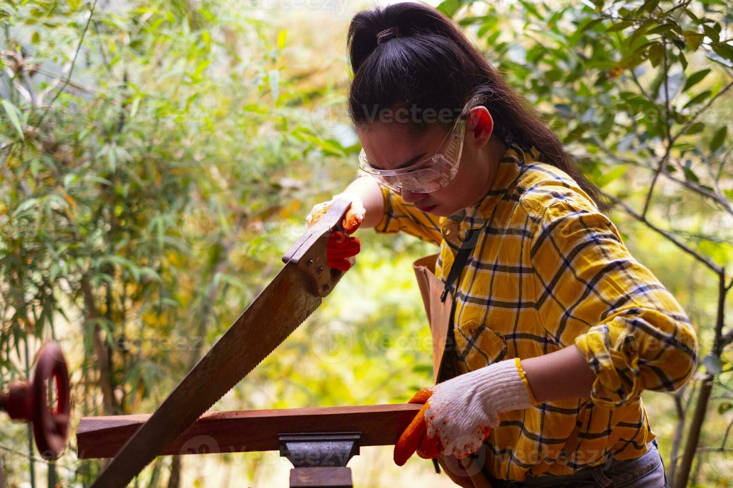 mulher em pé serrando tábua de madeira foto
