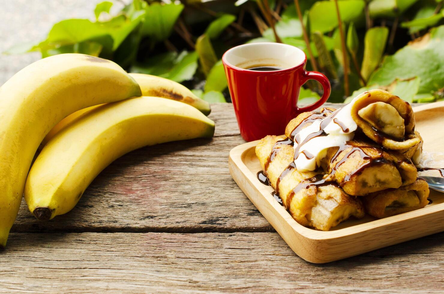 Torrada francesa de banana e bebidas com café em fundos de mesa de madeira foto