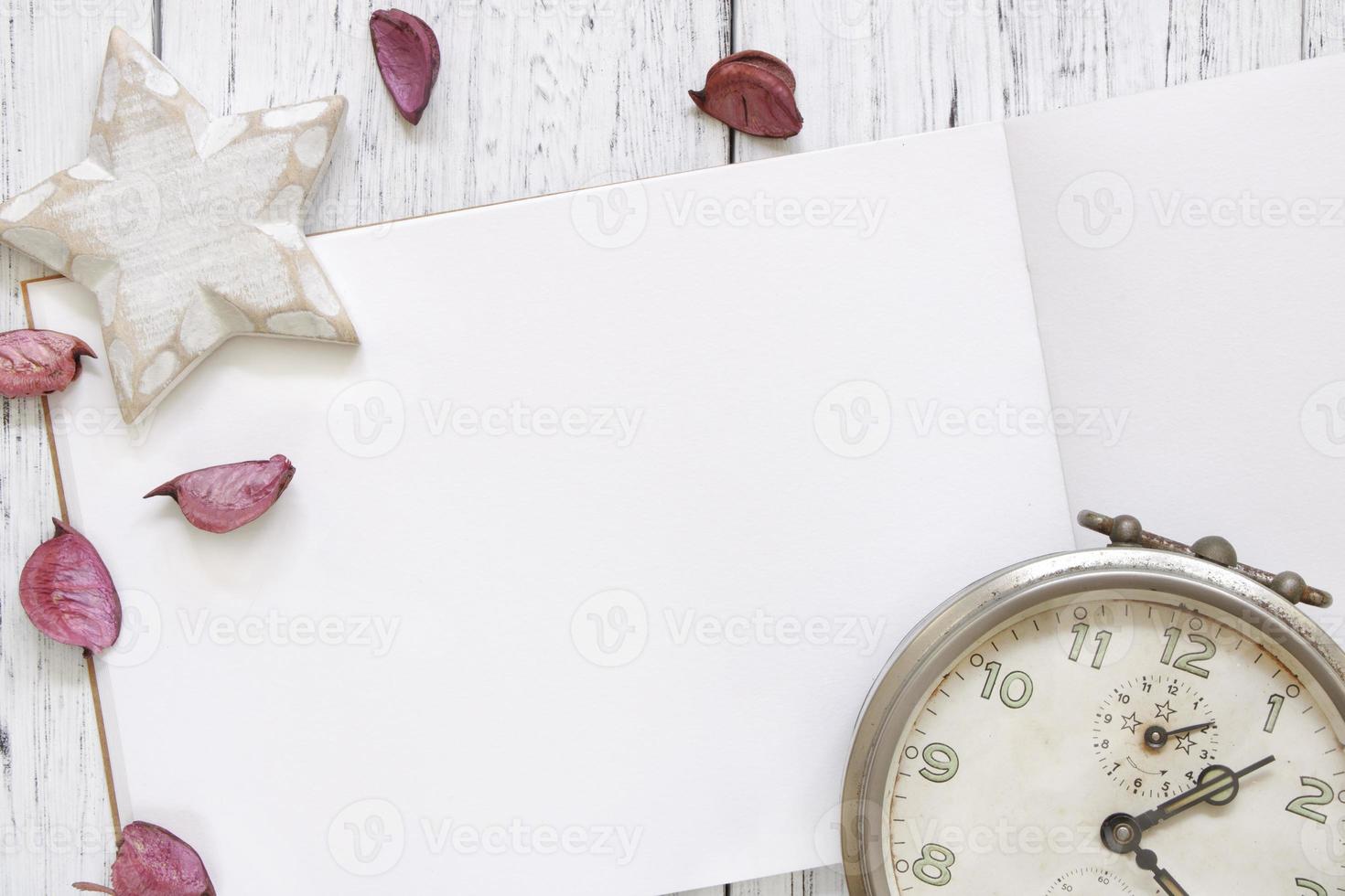 mesa de madeira pintada de branco, pétalas de flores, despertador vintage estrela artesanal foto