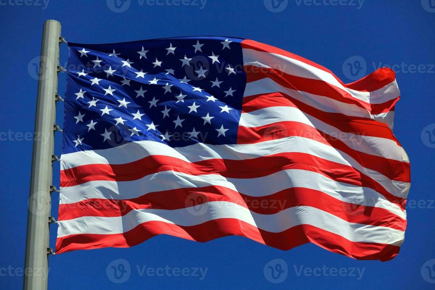 americano bandeira acenando dentro a vento contra azul céu foto