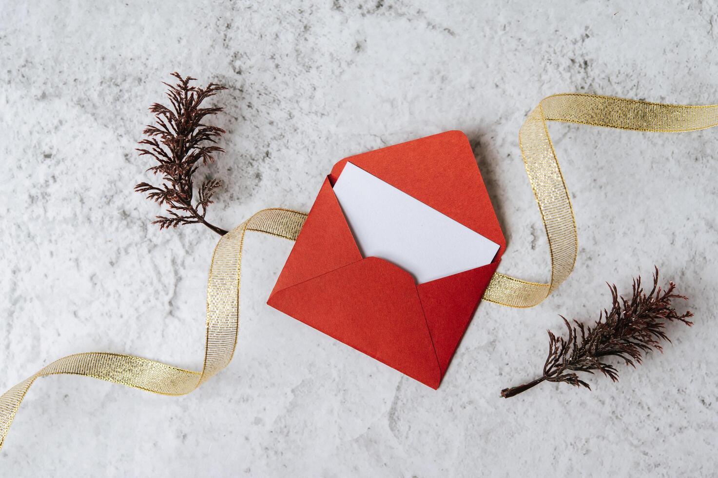 um cartão em branco com um envelope vermelho e uma folha é colocado em um fundo branco foto