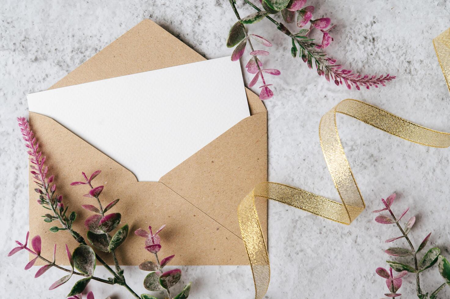 um cartão em branco com um envelope e uma flor é colocado em um fundo branco foto