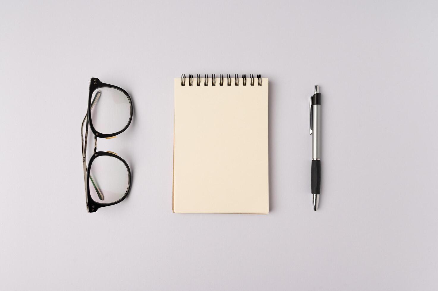 óculos de caderno e caneta em fundo branco foto