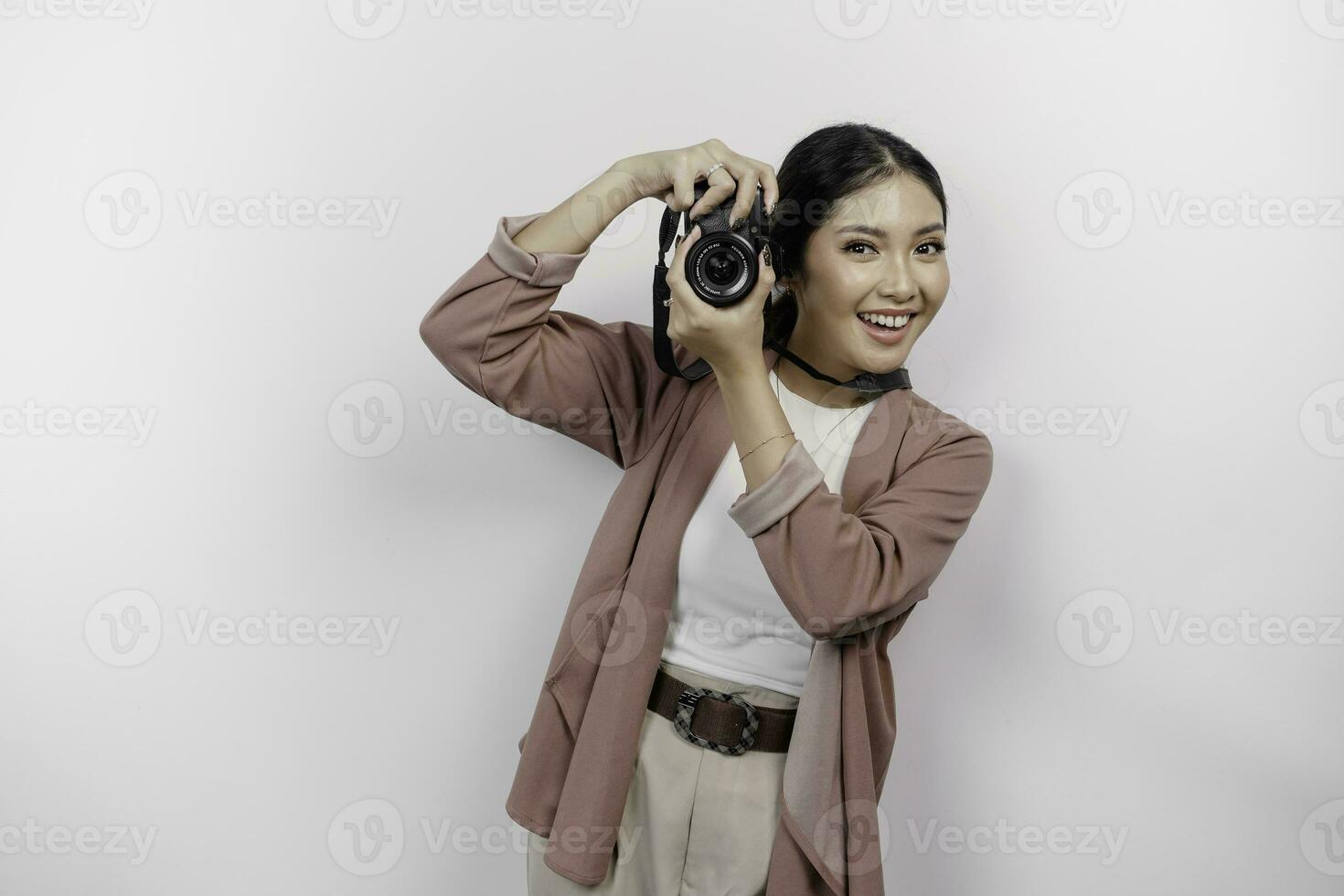 alegre jovem ásia mulher turista em pé com Câmera levando foto isolado em branco estúdio fundo