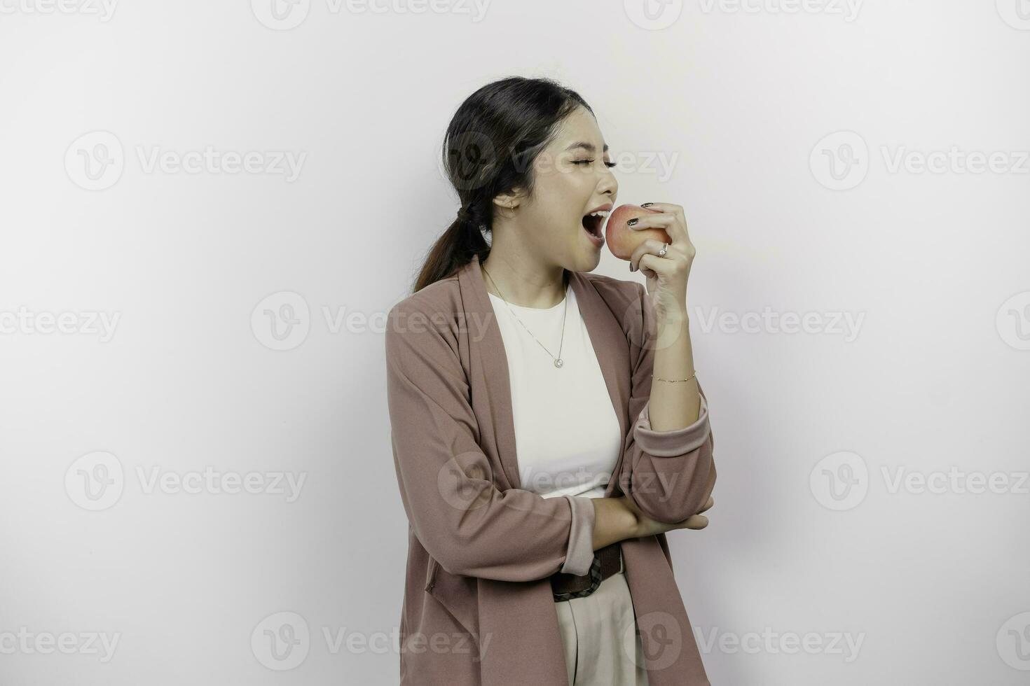 com fome ásia mulher empregado é feliz sobre Beliscando maçã, boca mordida saudável Comida para dieta e orgânico estilo de vida, isolado de branco fundo foto