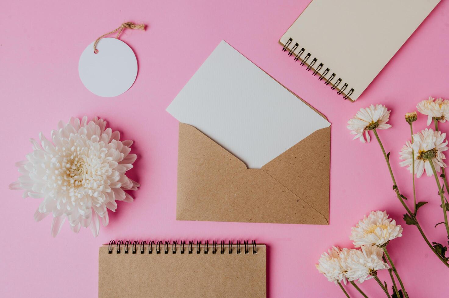 envelope marrom, etiqueta, caderno com cartão em branco e flor foto