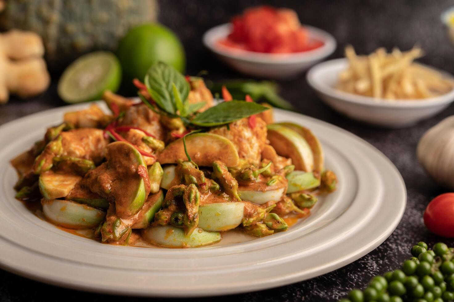 curry verde seco com frango em pratos brancos sobre cimento preto foto