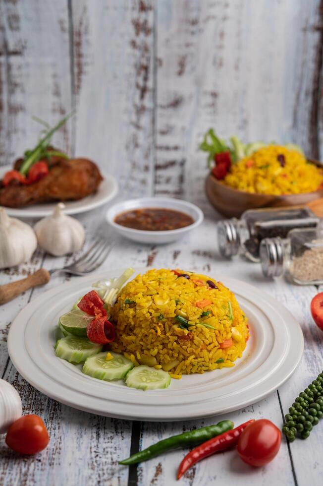 arroz de açafrão em um prato branco com especiarias em um piso de madeira branco foto