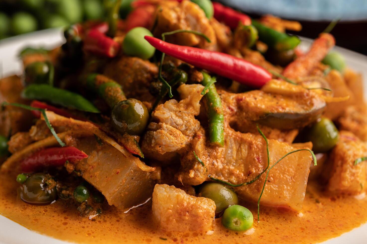 curry vermelho com carne de porco em um prato branco foto