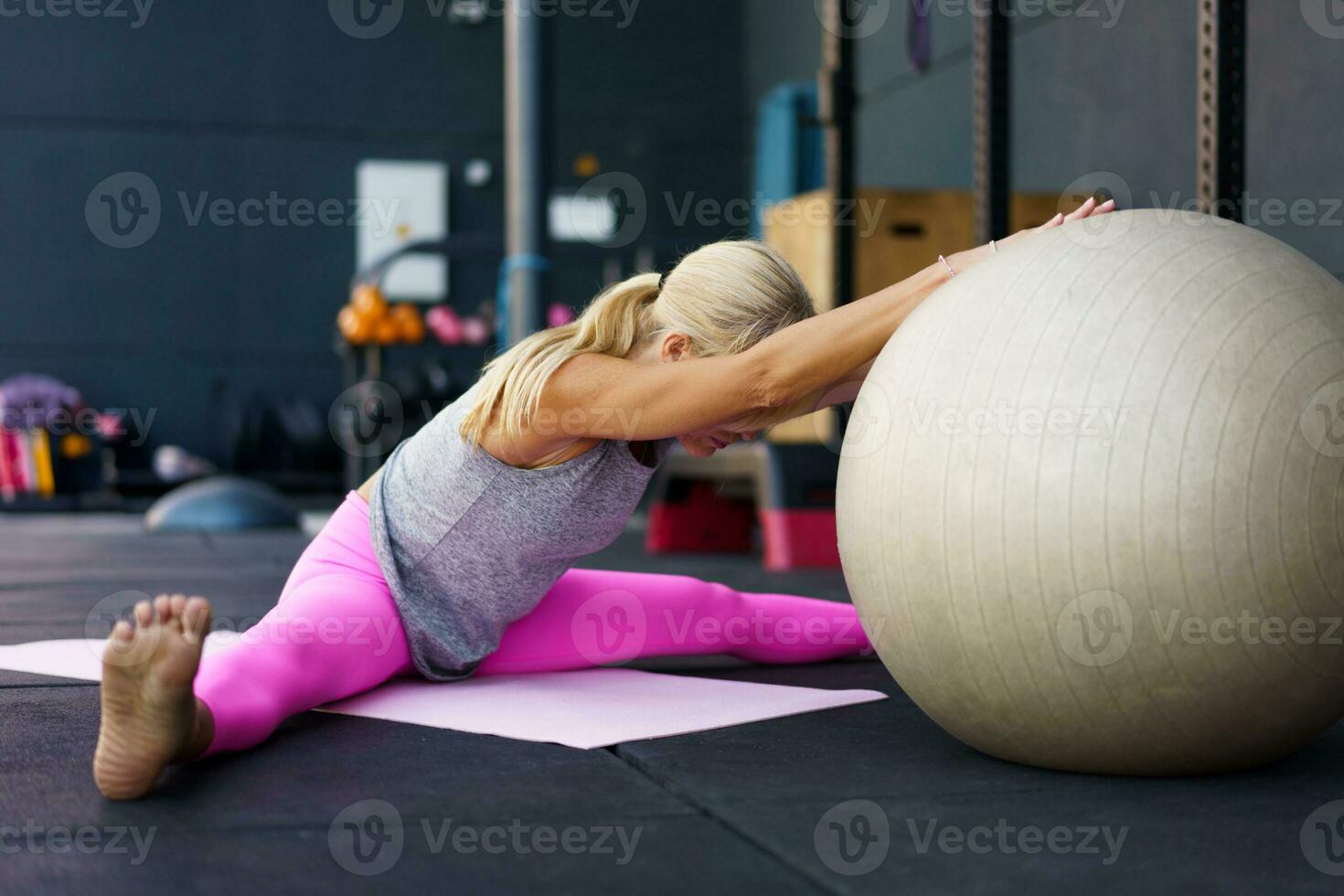 irreconhecível mulher fazendo alongamento exercício dentro Academia foto