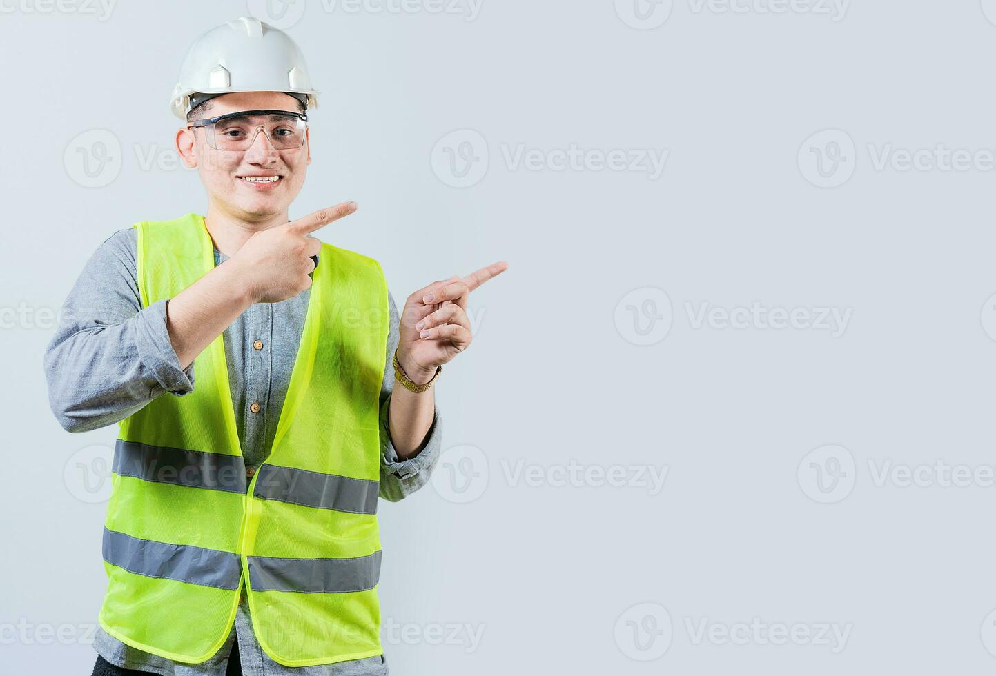 alegre engenheiro com capacete apontando a parte, de lado isolado. bonito engenheiro apontando a propaganda isolado foto