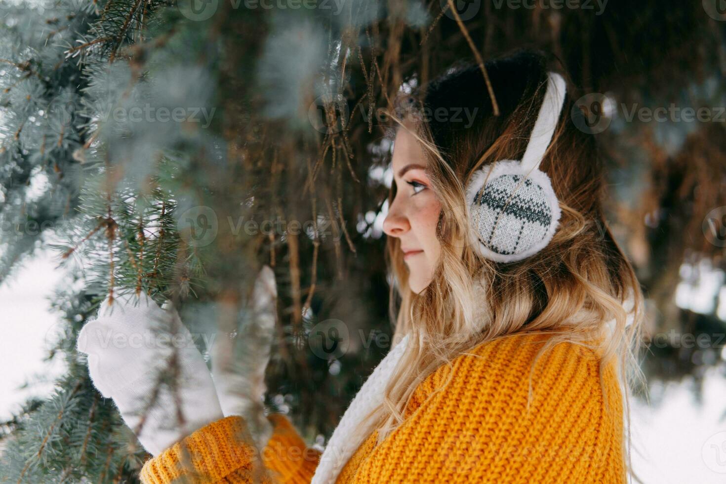 adolescente Loiras dentro uma amarelo suéter lado de fora dentro inverno. uma Adolescência menina em uma andar dentro inverno roupas dentro uma Nevado floresta foto