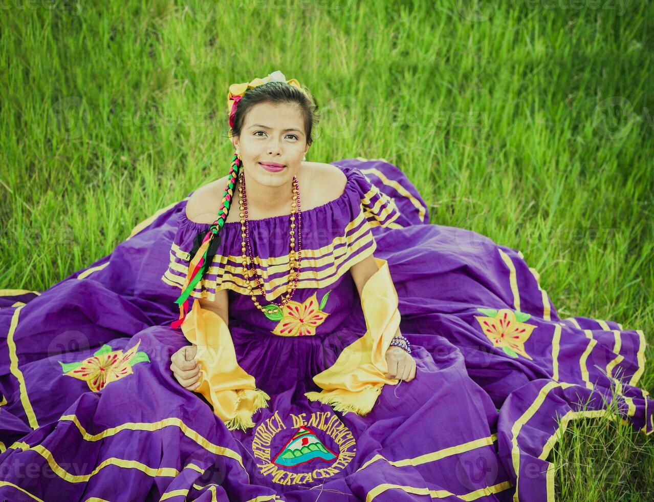 retrato do nicaraguense mulher dentro folk traje sentado em a grama, jovem nicaraguense mulher dentro tradicional folk traje sentado em a Relva dentro a campo foto