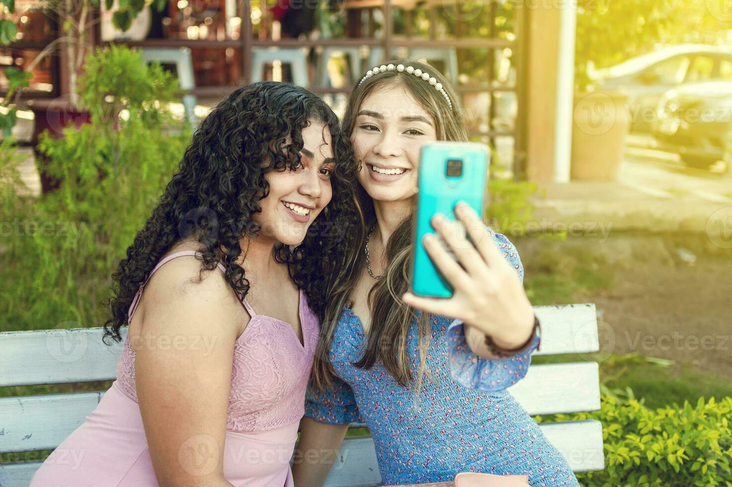 dois bonita meninas sentado em uma Banco levando uma selfie, meninas sorridente e levando uma selfie, fraternal amizade conceito foto