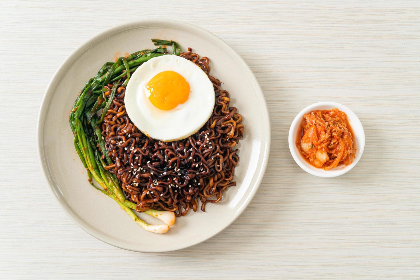 Molho preto picante coreano macarrão instantâneo com ovo frito e kimchi foto
