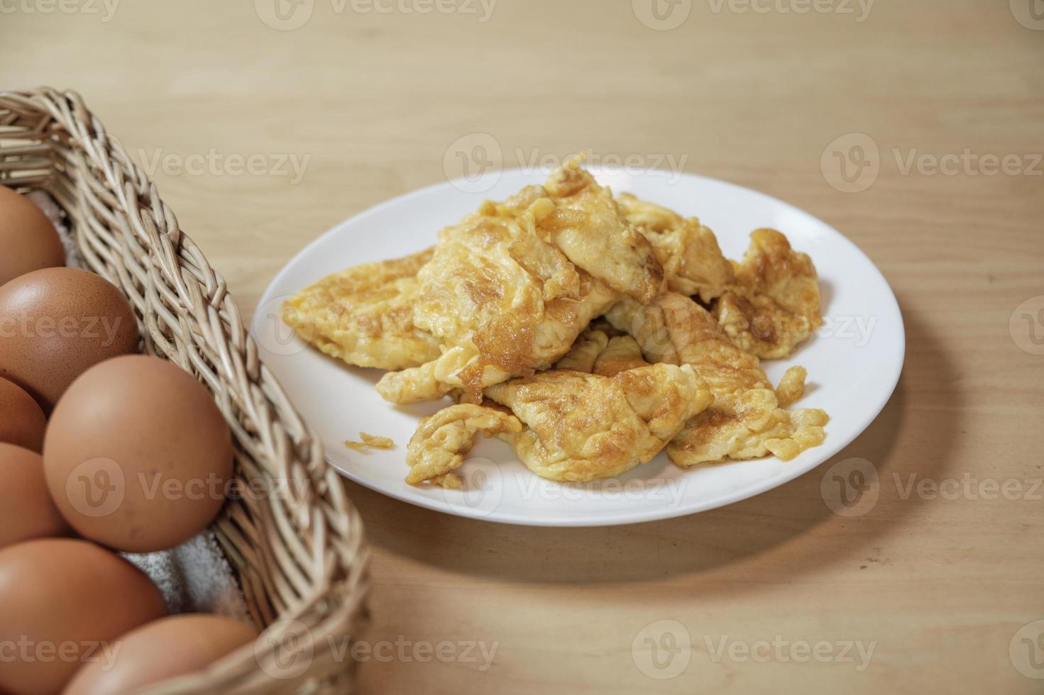 omeletes em chapa branca, cesta de ovos na mesa da cozinha em casa. foto