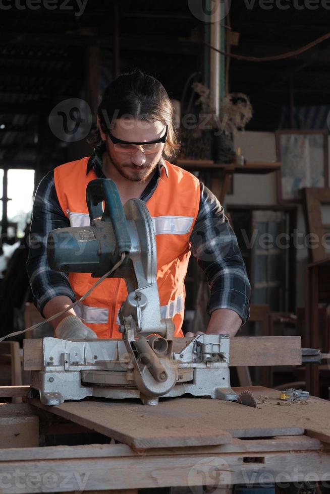 jovem carpinteiro caucasiano está trabalhando em uma fábrica de serraria de madeira. foto