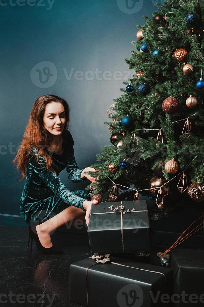 linda mulher com caixas de presente perto da árvore de natal foto