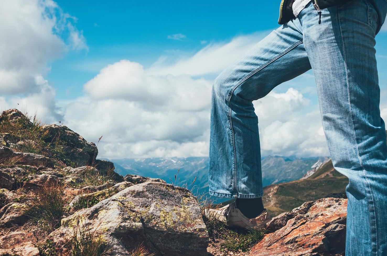 pernas de homem em pé no topo do penhasco foto