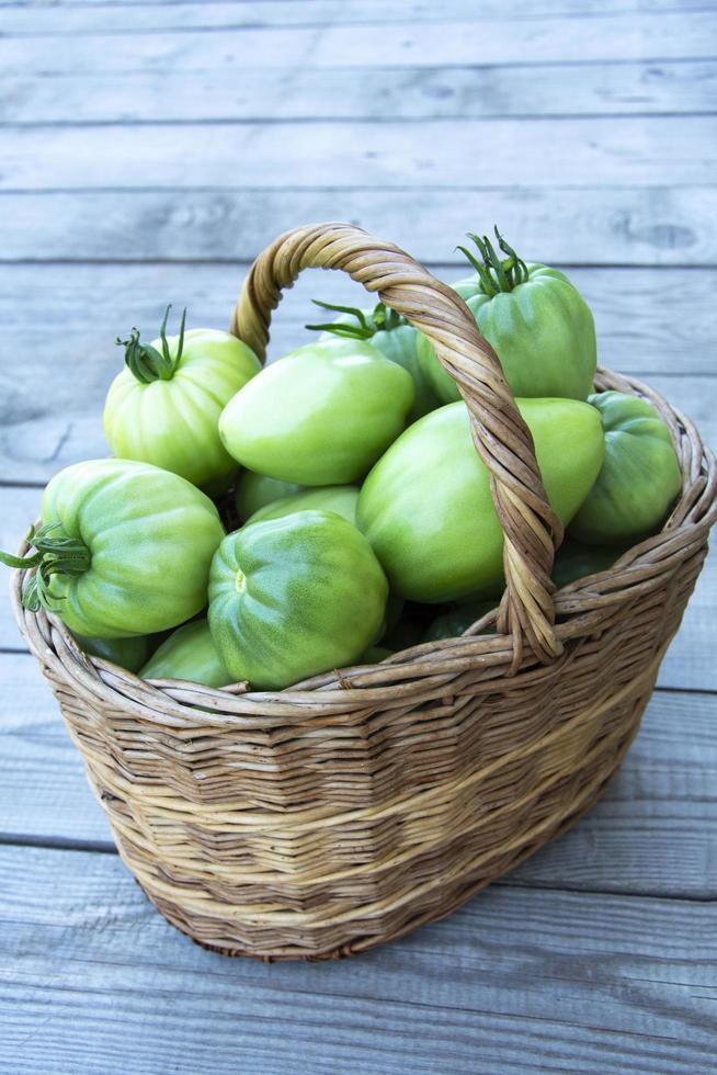 uma cesta de vime com tomates verdes foto